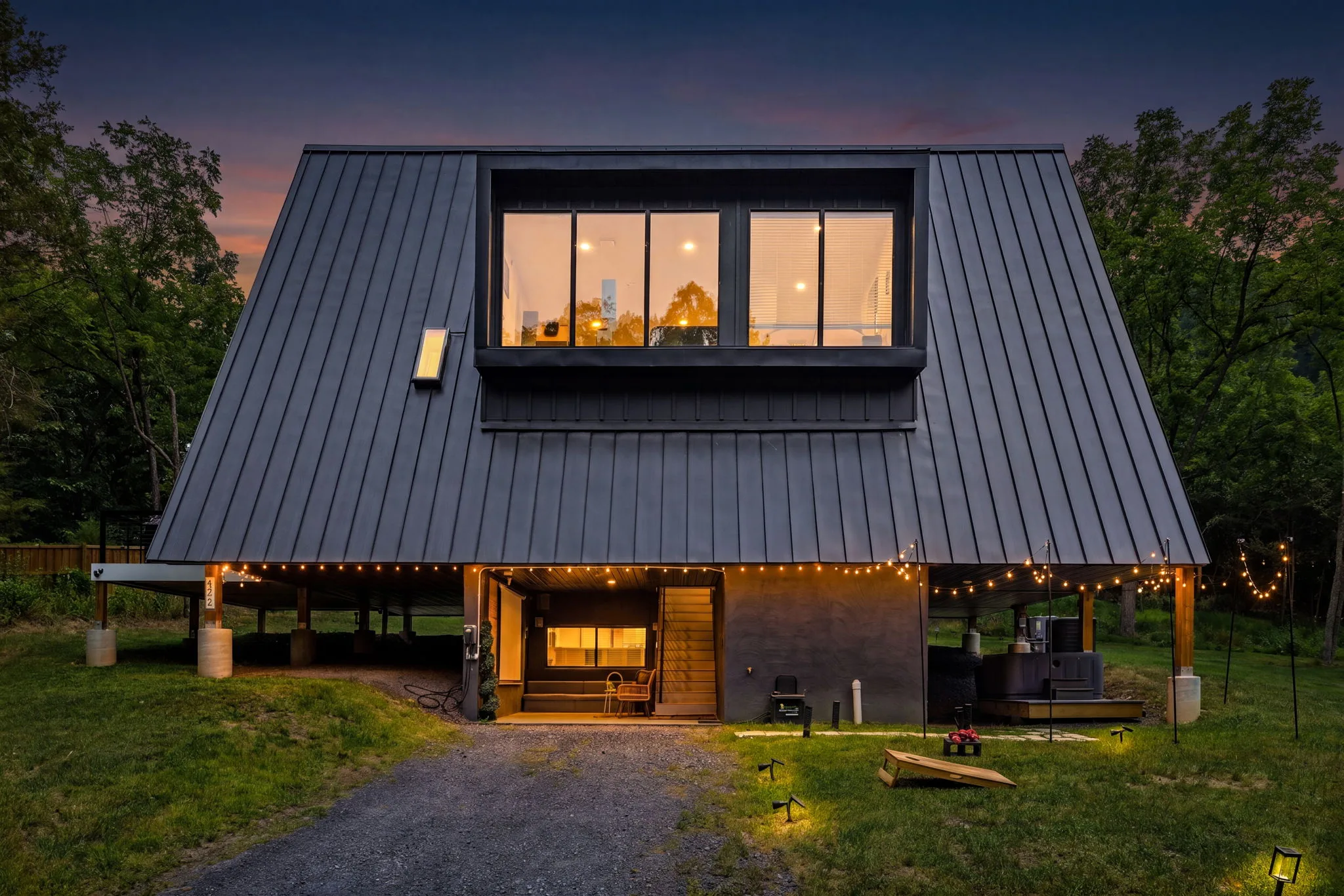 The modern black A-frame Chalet illuminated at twilight