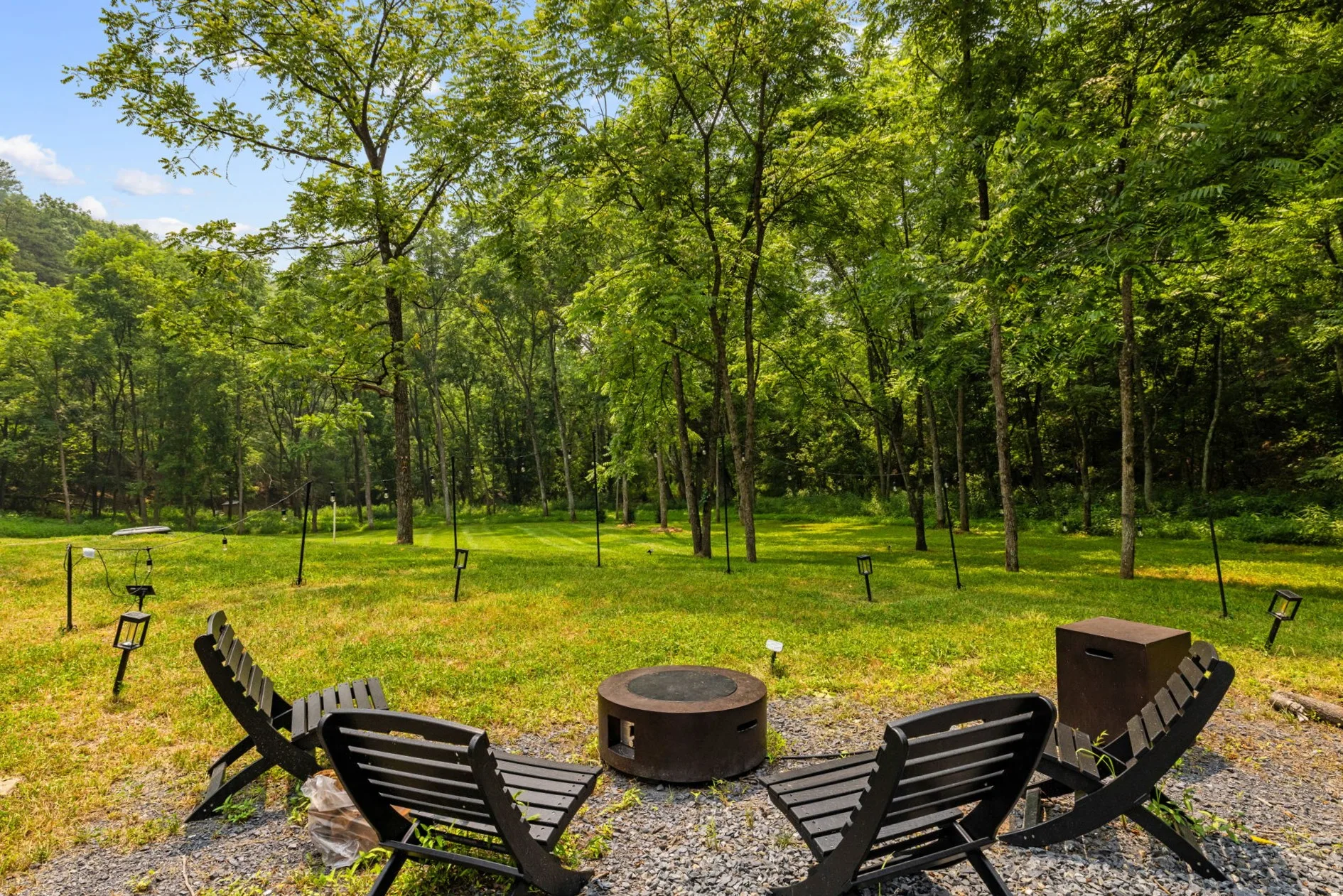 Four Adirondack chairs arranged around the woodland fire pit