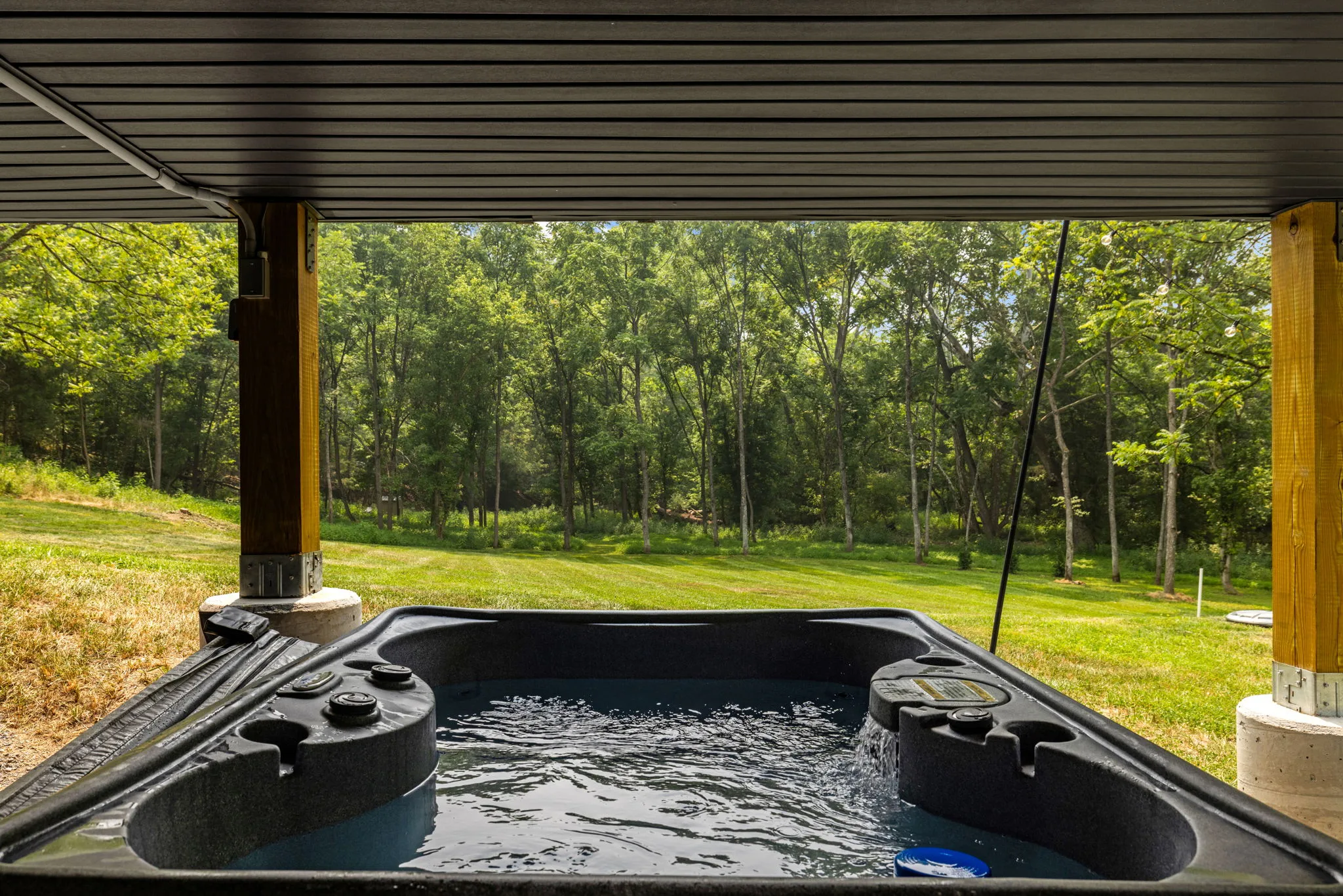 Covered hot tub facing the private wooded lawn