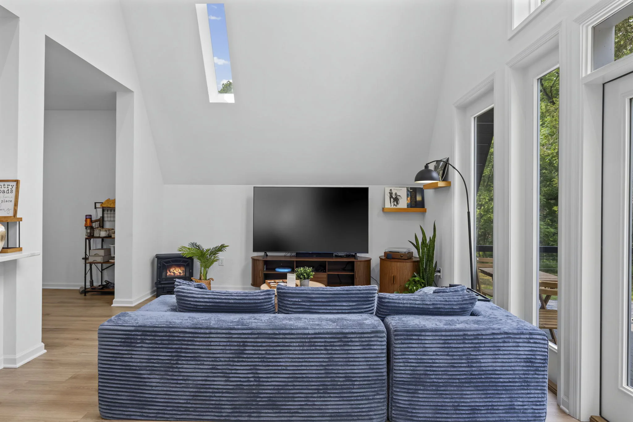 Double-height living room with blue sectional and woodland views